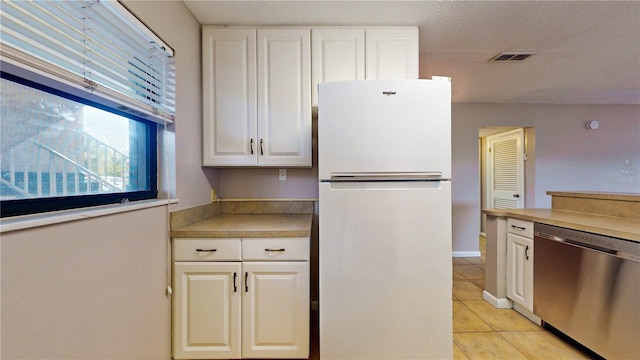 kitchen featuring a textured ceiling, light tile patterned floors, white refrigerator, dishwasher, and white cabinets