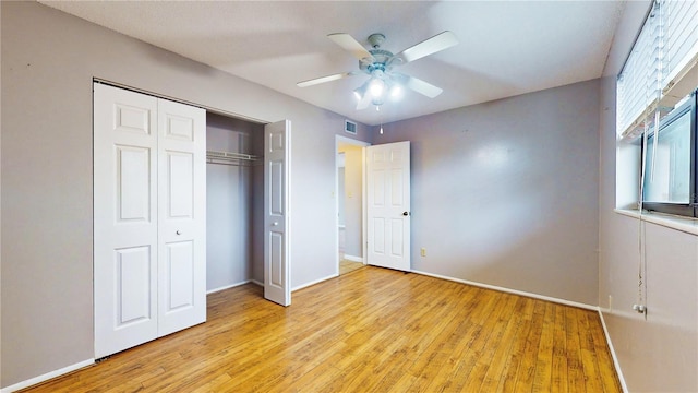 unfurnished bedroom with ceiling fan, light wood-type flooring, and a closet