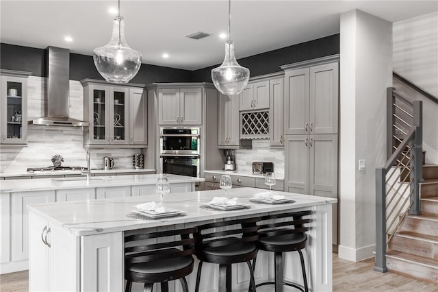 kitchen with decorative light fixtures, a breakfast bar area, and wall chimney exhaust hood