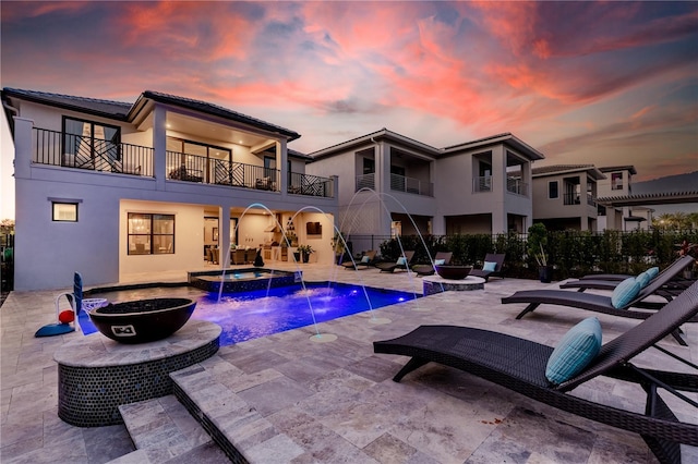 pool at dusk featuring pool water feature and a patio area