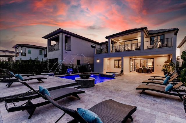 pool at dusk with an outdoor living space, a patio, pool water feature, and a jacuzzi