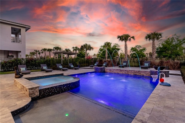 pool at dusk featuring an in ground hot tub, pool water feature, and a patio area