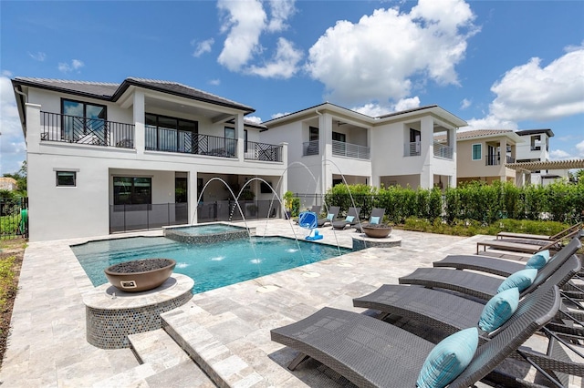 back of house featuring pool water feature, a balcony, a swimming pool with hot tub, and a patio