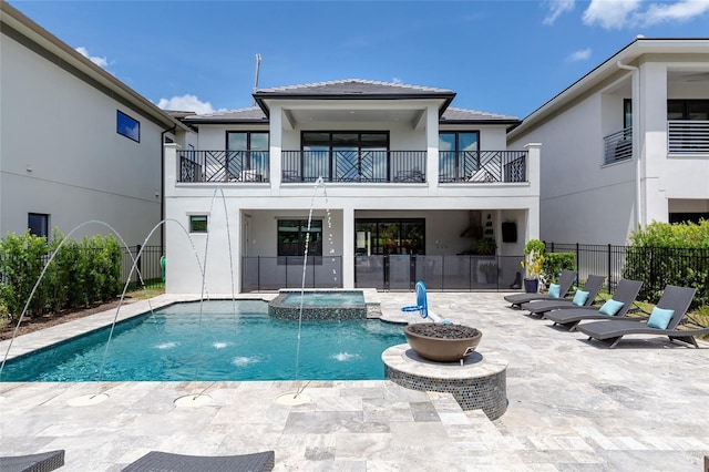 rear view of property with a swimming pool with hot tub, a patio, and pool water feature