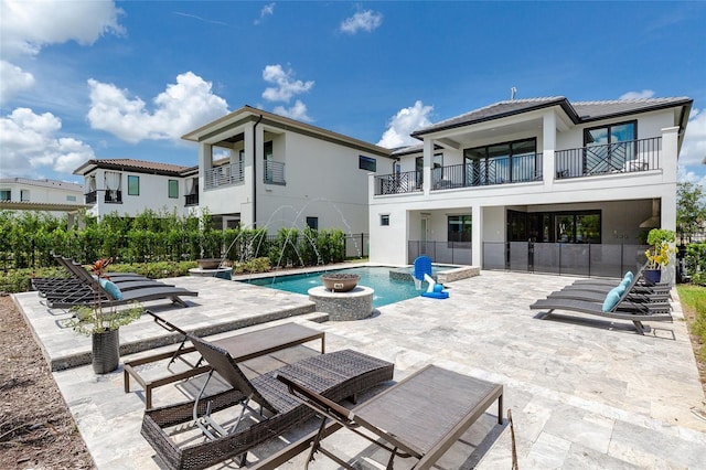 rear view of house with a balcony, a fenced in pool, and a patio area