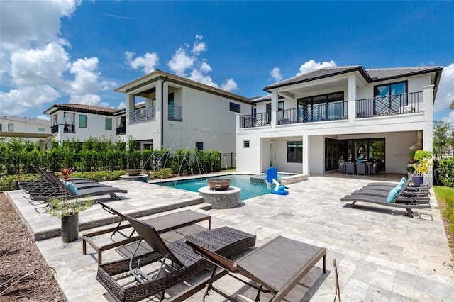 back of property featuring pool water feature, a balcony, a fenced in pool, and a patio