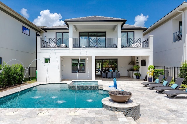 back of property featuring a patio, pool water feature, and a balcony