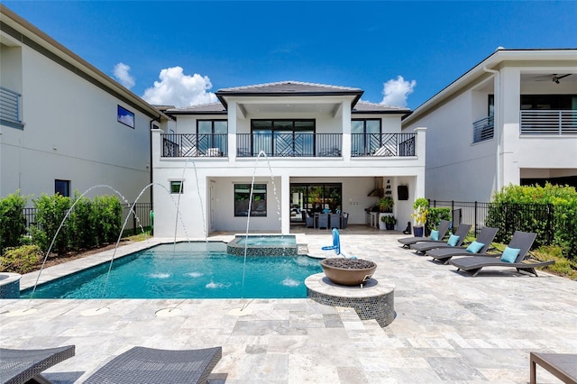 back of house with pool water feature, a balcony, a pool with hot tub, and a patio area