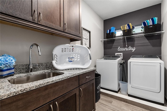 clothes washing area featuring cabinets, sink, independent washer and dryer, and light hardwood / wood-style floors