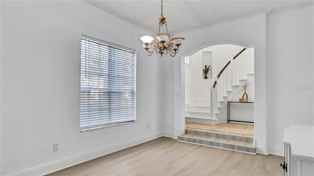 spare room featuring a chandelier and light wood-type flooring