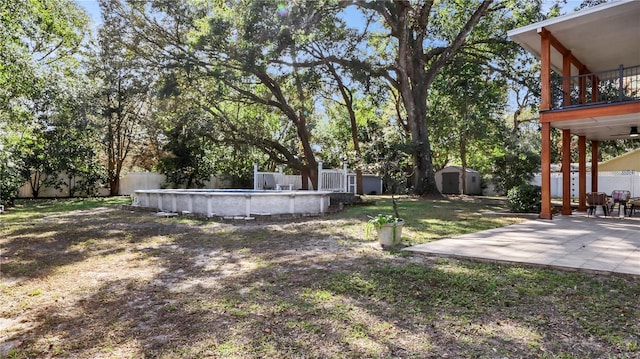 view of yard with a storage shed, a patio area, a balcony, and a fenced in pool