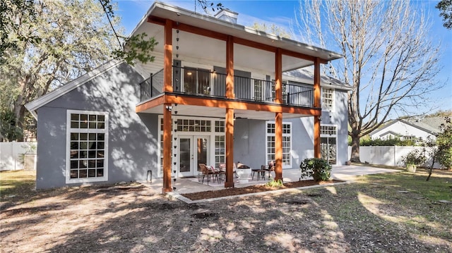 rear view of house with a patio, a balcony, and french doors