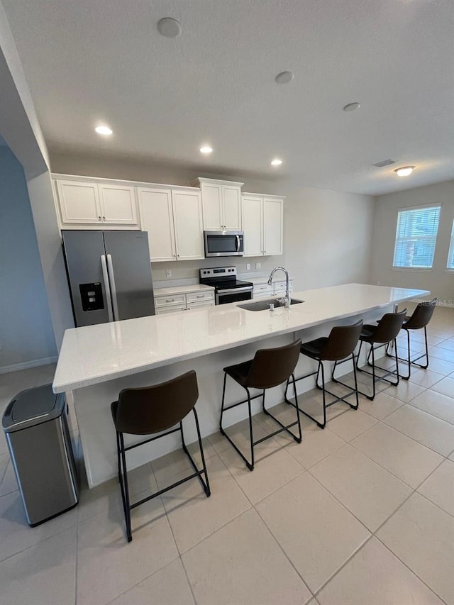 kitchen with white cabinetry, stainless steel appliances, a kitchen breakfast bar, and sink