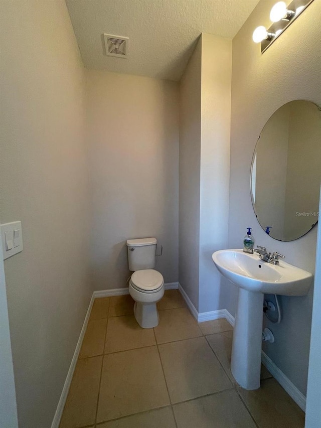 bathroom with toilet, tile patterned flooring, and a textured ceiling