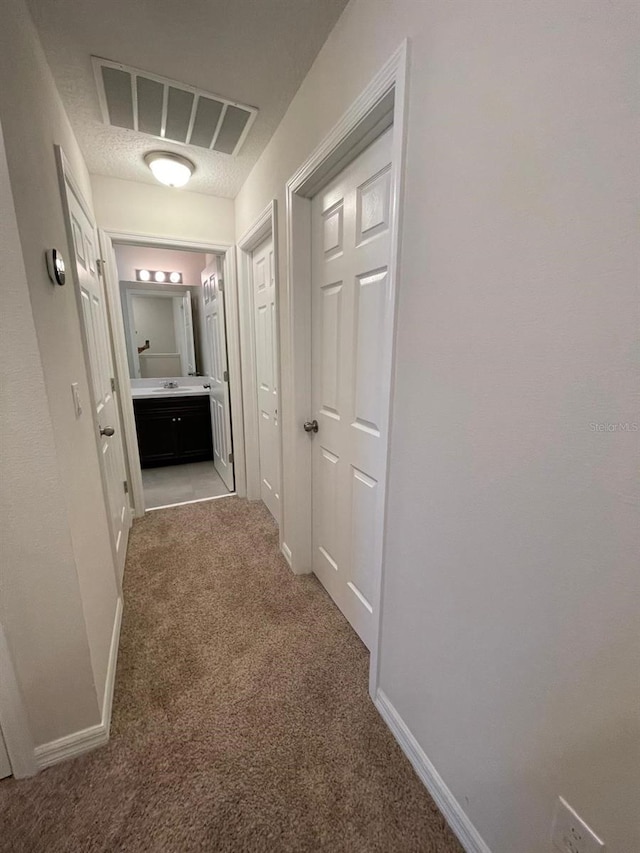 hallway with carpet flooring and a textured ceiling