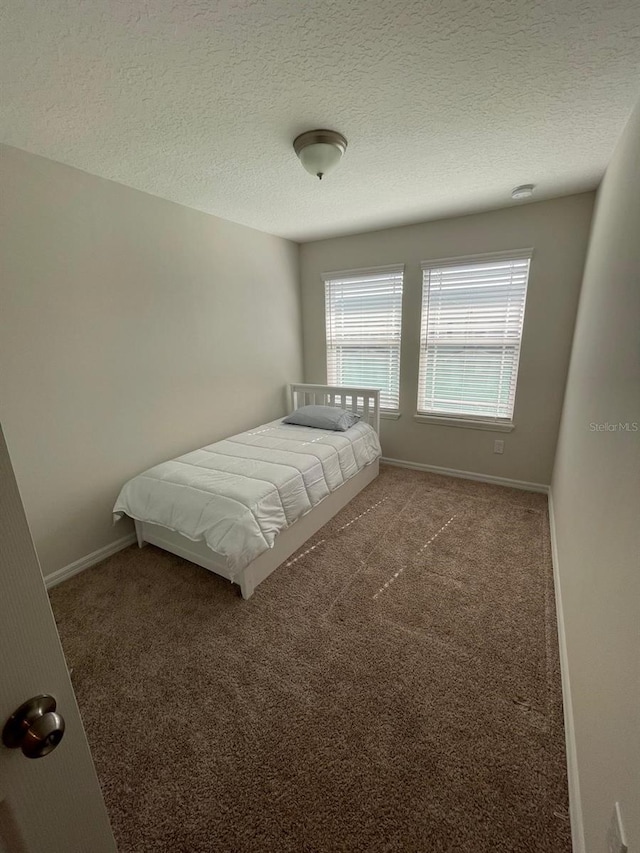 unfurnished bedroom featuring a textured ceiling and carpet