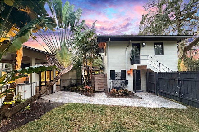 back house at dusk with a yard and a patio