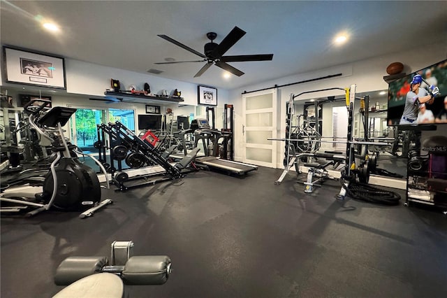 workout area with ceiling fan and a barn door