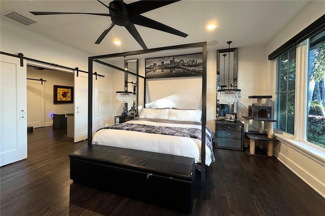 bedroom featuring dark hardwood / wood-style flooring and a barn door