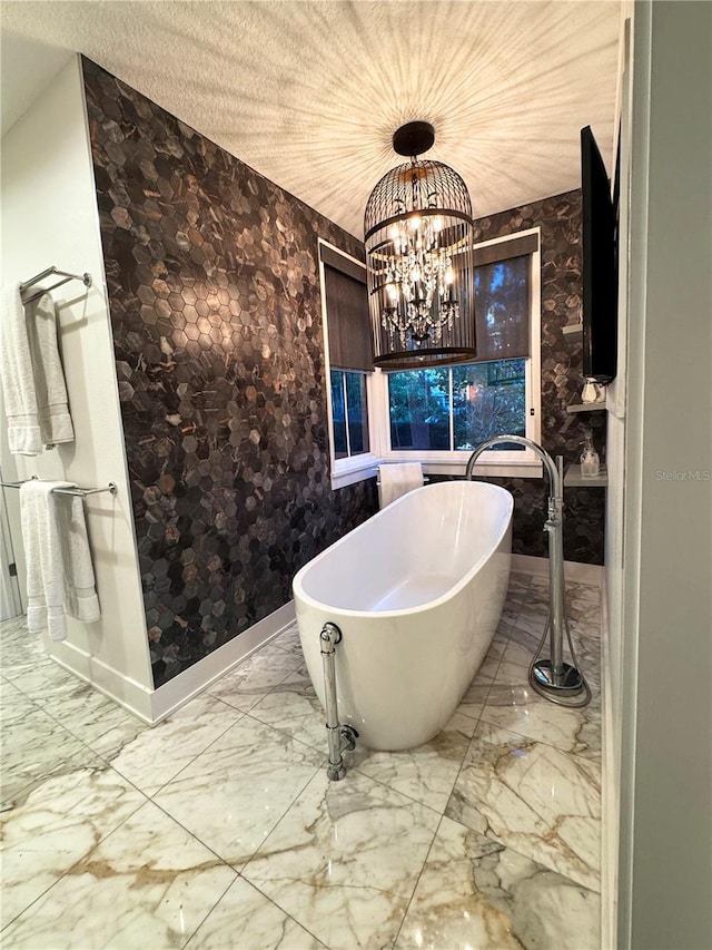 bathroom with a tub to relax in and a notable chandelier