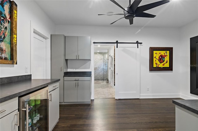 kitchen featuring dark hardwood / wood-style floors, beverage cooler, ceiling fan, and a barn door