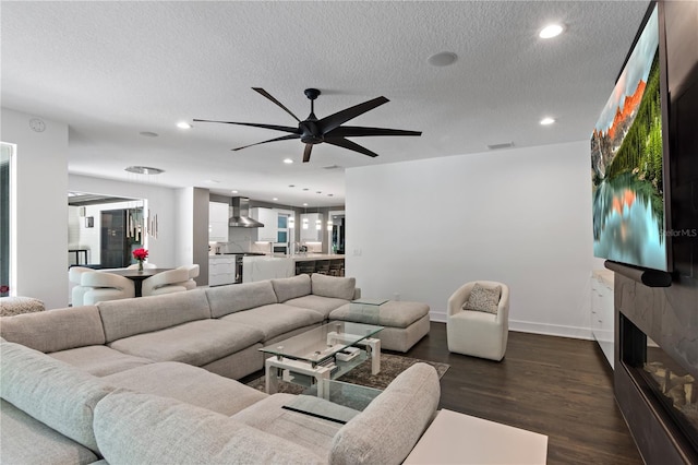 living room with dark wood-type flooring, ceiling fan, and a textured ceiling