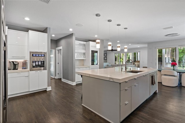 kitchen with pendant lighting, white cabinetry, sink, dark hardwood / wood-style flooring, and a kitchen island with sink