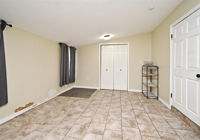 unfurnished bedroom featuring lofted ceiling, a closet, and light tile patterned flooring