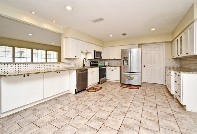 kitchen featuring sink, white cabinetry, stainless steel appliances, tasteful backsplash, and light stone countertops