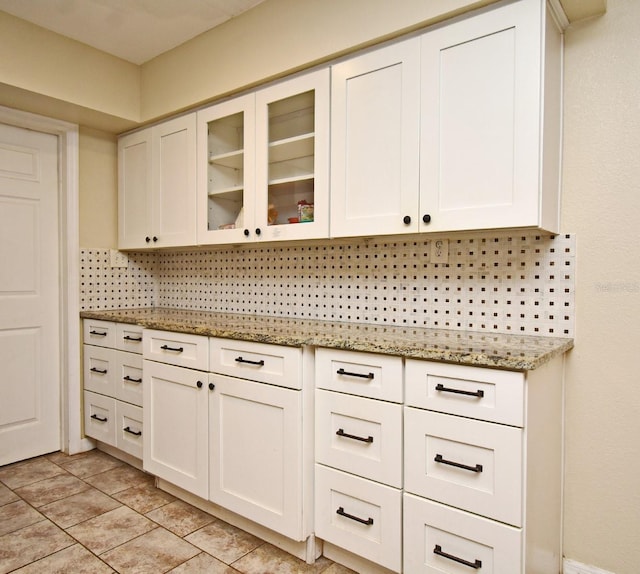 kitchen featuring decorative backsplash, light stone countertops, and white cabinets