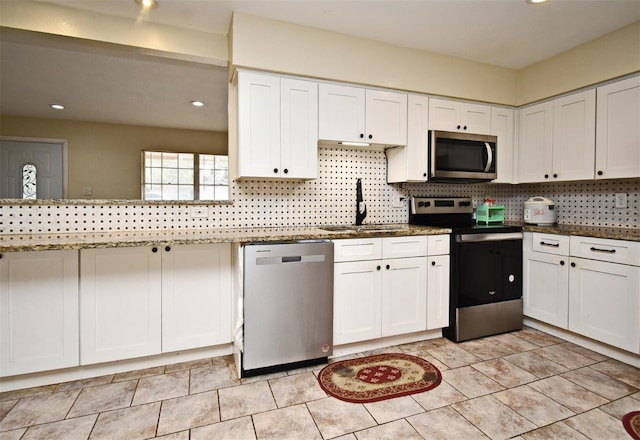 kitchen with sink, dark stone countertops, stainless steel appliances, tasteful backsplash, and white cabinets