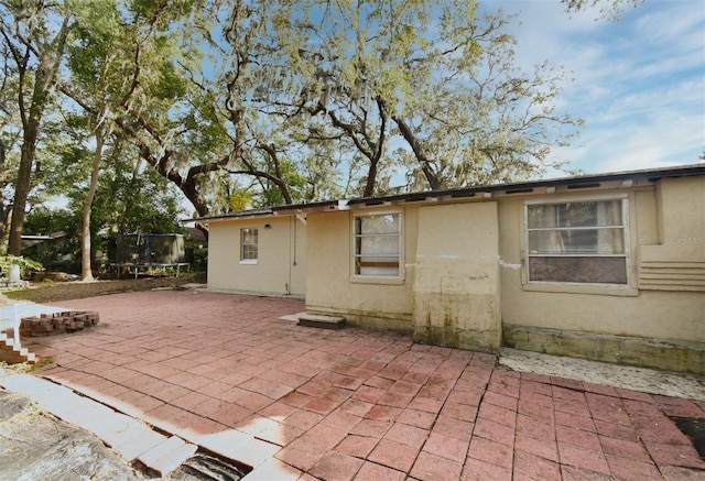 back of property featuring a trampoline and a patio area