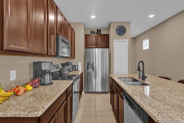 kitchen featuring sink, appliances with stainless steel finishes, a kitchen island with sink, light stone countertops, and light tile patterned flooring