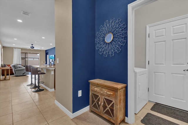 hallway featuring washer / dryer and light tile patterned floors