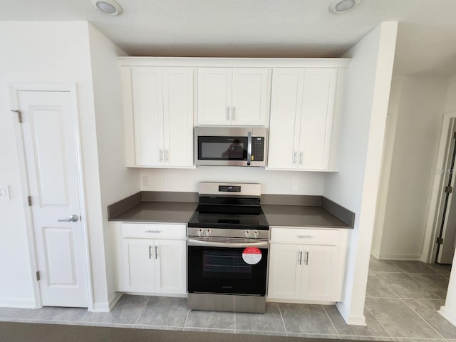 kitchen with white cabinetry, light tile patterned floors, and stainless steel appliances