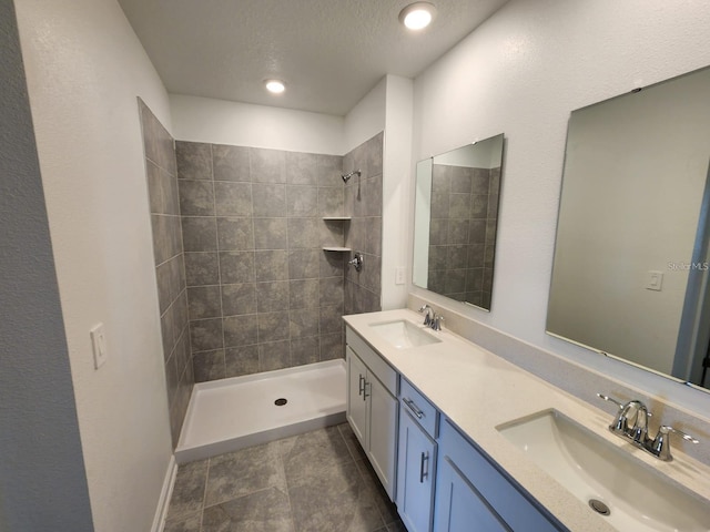 bathroom with vanity, a tile shower, and a textured ceiling