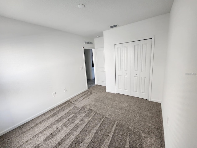 unfurnished bedroom with dark carpet and a closet