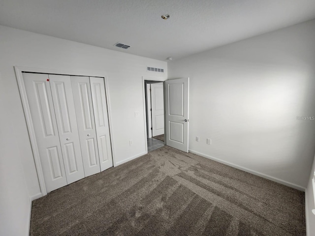 unfurnished bedroom with dark carpet and a closet