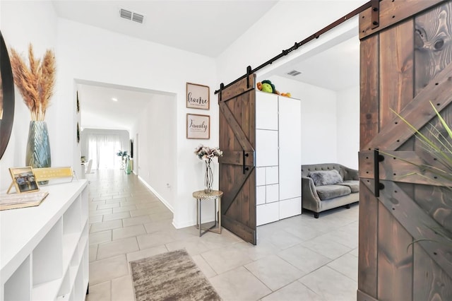 hall featuring light tile patterned flooring and a barn door