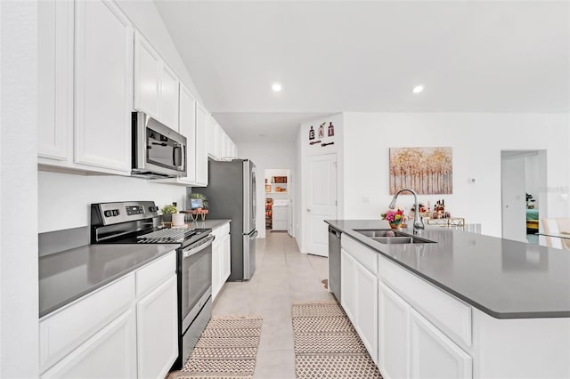 kitchen featuring sink, light tile patterned floors, appliances with stainless steel finishes, a kitchen island with sink, and white cabinets