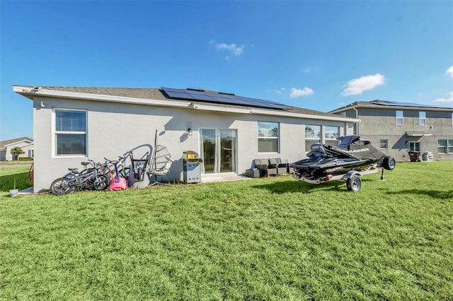 back of property featuring a lawn and solar panels