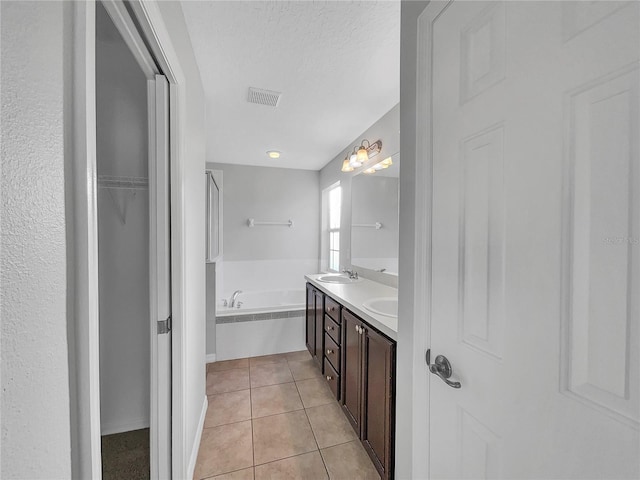 bathroom with tile patterned flooring, a bathing tub, vanity, and a textured ceiling