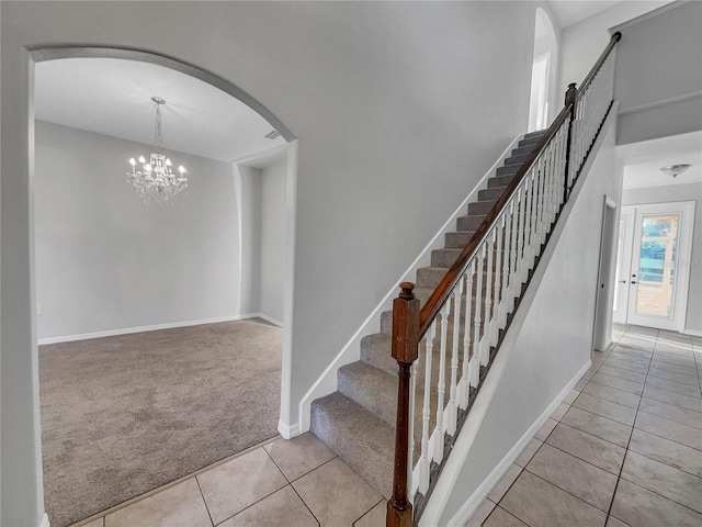 staircase featuring tile patterned floors, a chandelier, and a high ceiling