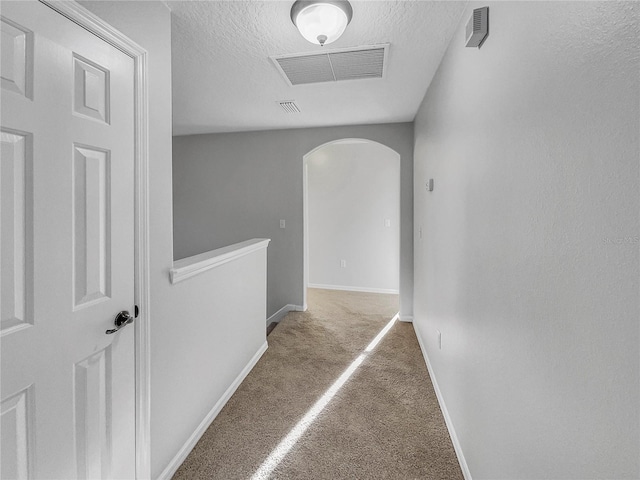 hallway with carpet floors and a textured ceiling