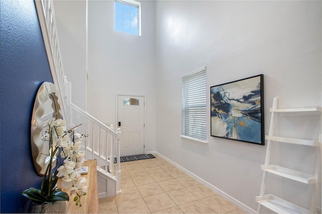 entrance foyer featuring light tile patterned floors and a towering ceiling