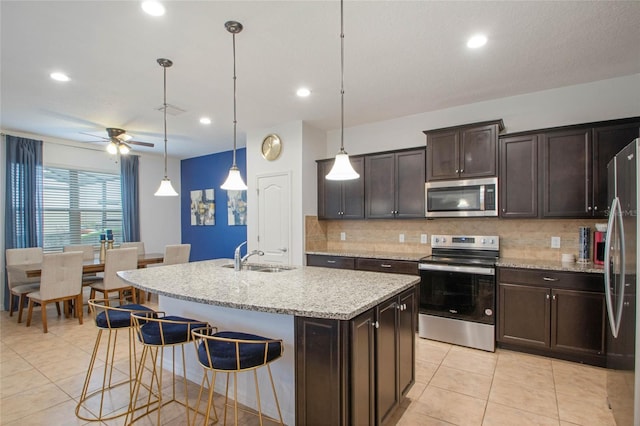 kitchen with appliances with stainless steel finishes, pendant lighting, sink, a kitchen island with sink, and dark brown cabinetry