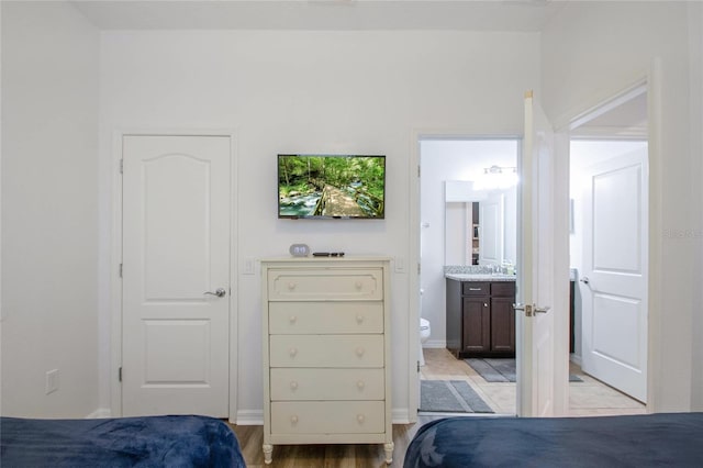 bedroom featuring ensuite bathroom and light wood-type flooring