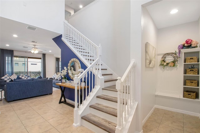 staircase featuring ceiling fan, tile patterned floors, and a high ceiling