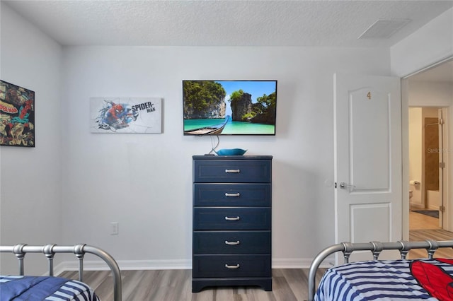 bedroom with a textured ceiling and light wood-type flooring