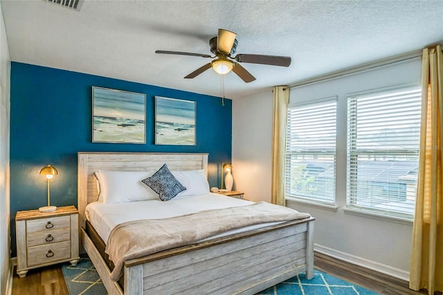 bedroom featuring ceiling fan, dark hardwood / wood-style floors, and a textured ceiling